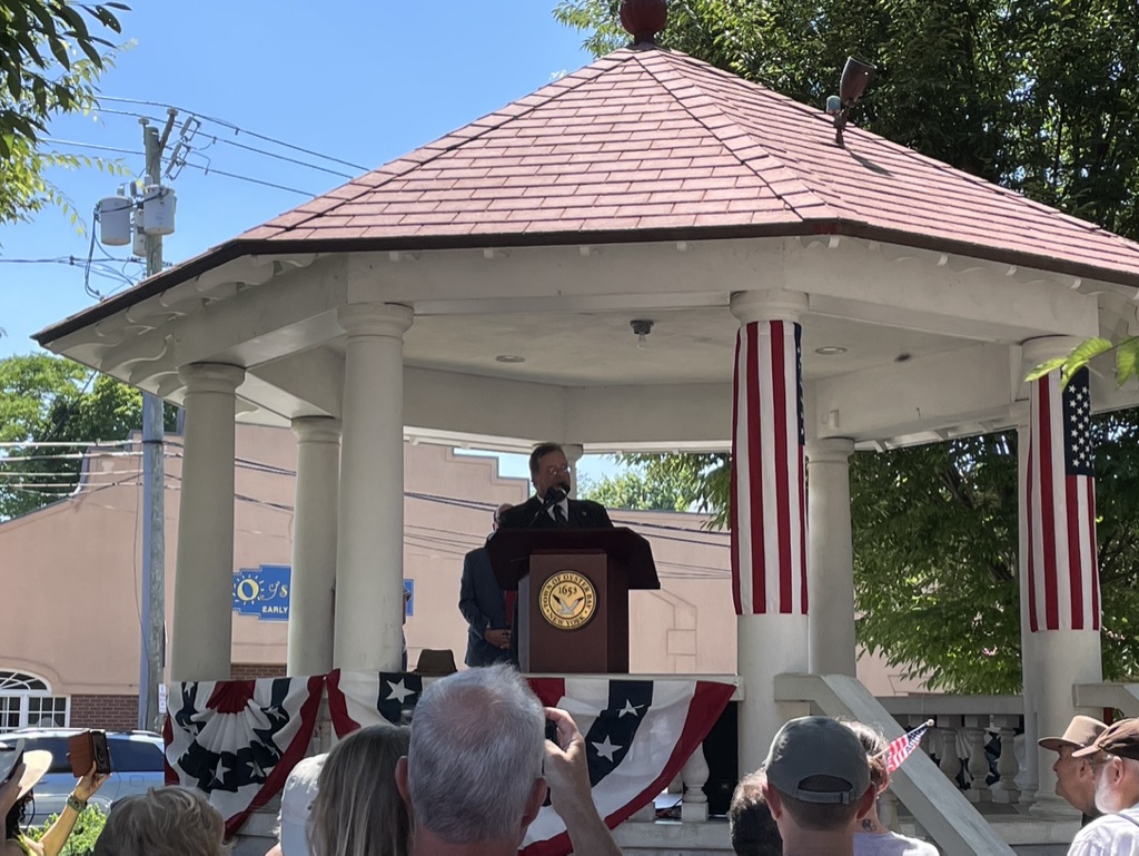 Joe addressing a gathering from an outdoor bandstand